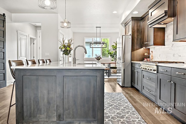kitchen with a sink, light countertops, stainless steel appliances, and dark wood-type flooring