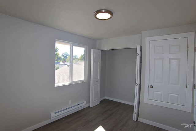 unfurnished bedroom with dark hardwood / wood-style flooring, a closet, and baseboard heating