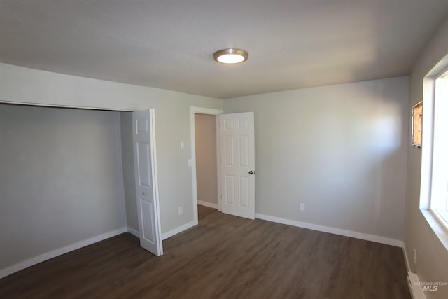 unfurnished bedroom with a closet and dark hardwood / wood-style floors