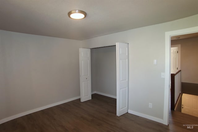 unfurnished bedroom featuring a closet and dark hardwood / wood-style floors