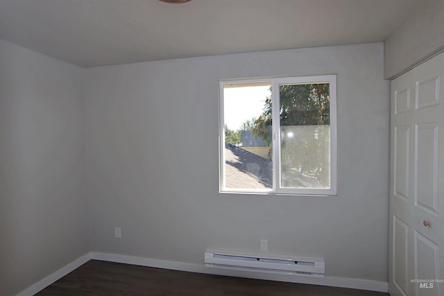 unfurnished room featuring dark wood-type flooring and a baseboard heating unit