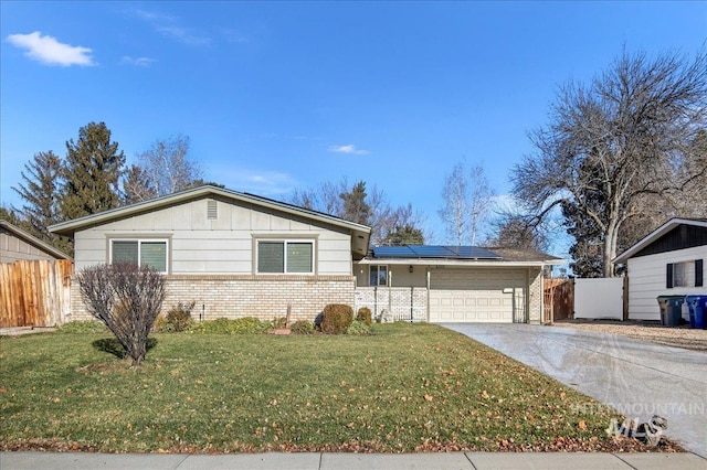 single story home with a front yard, solar panels, and a garage