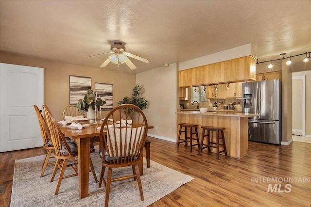 dining space with a textured ceiling, dark hardwood / wood-style flooring, ceiling fan, and sink