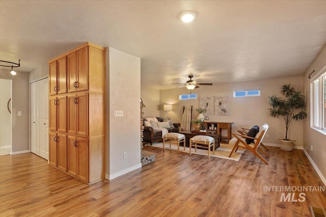 sitting room featuring ceiling fan, a textured ceiling, and light wood-type flooring