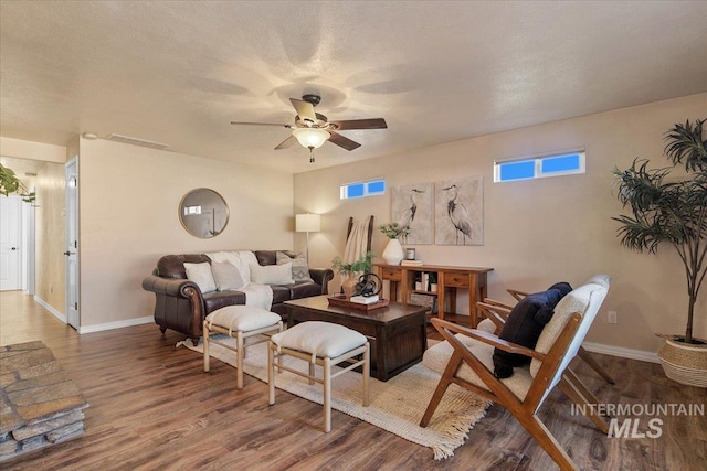 living room with hardwood / wood-style flooring, ceiling fan, and a textured ceiling