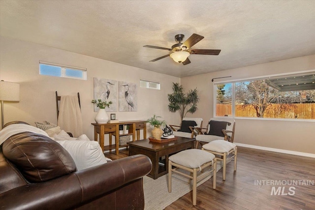 living room with a textured ceiling, dark hardwood / wood-style flooring, plenty of natural light, and ceiling fan