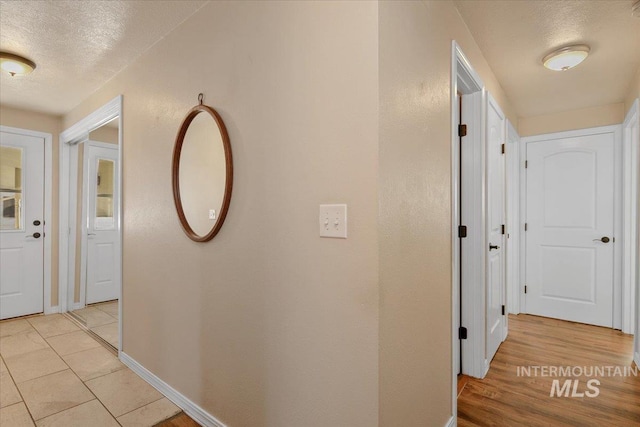 hall with light hardwood / wood-style floors and a textured ceiling