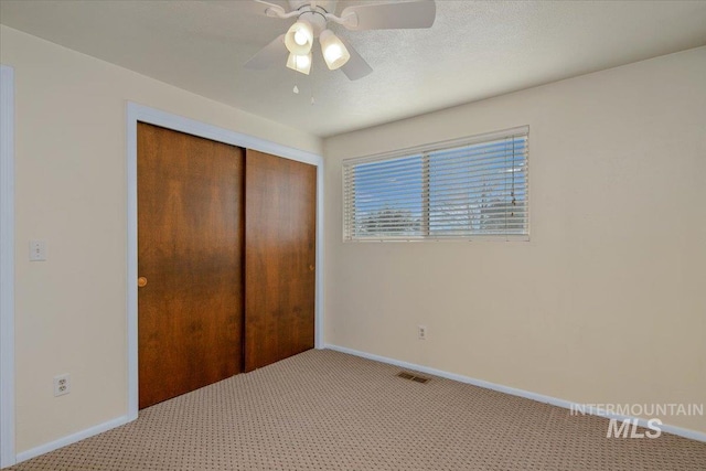 unfurnished bedroom featuring ceiling fan, a closet, and light colored carpet