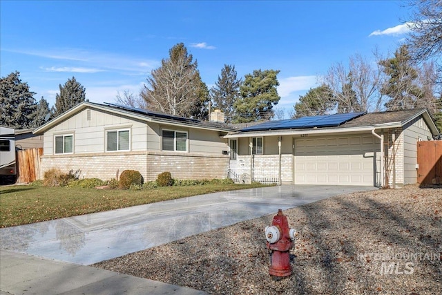 ranch-style house with a front lawn, a garage, and solar panels