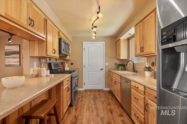 kitchen with decorative backsplash, sink, hardwood / wood-style flooring, and appliances with stainless steel finishes