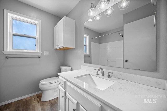 full bathroom featuring vanity, toilet, a shower, wood finished floors, and baseboards
