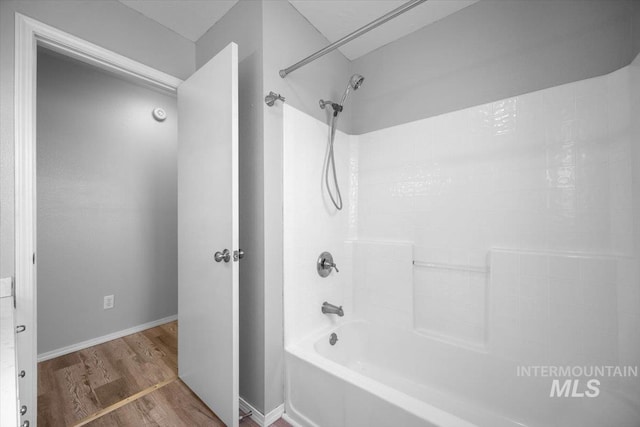 bathroom with baseboards, shower / bathing tub combination, and wood finished floors