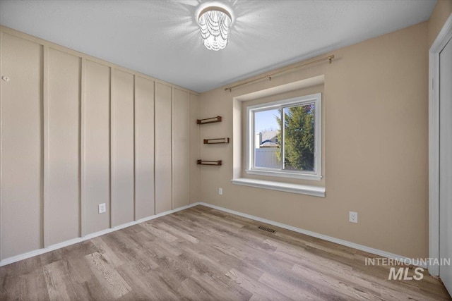 empty room featuring light wood-style flooring, baseboards, and visible vents