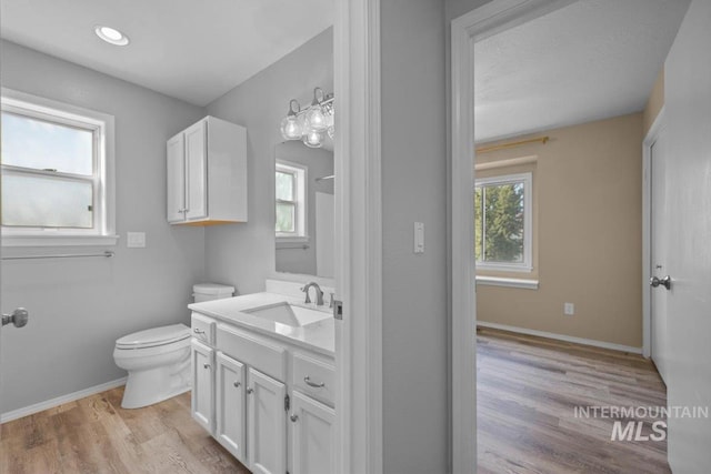 bathroom featuring toilet, vanity, wood finished floors, and baseboards