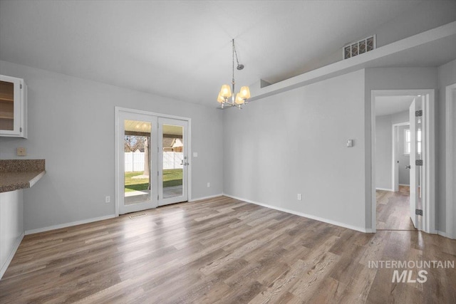 unfurnished dining area with a chandelier, visible vents, baseboards, and wood finished floors