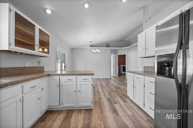 kitchen with light wood-style floors, an inviting chandelier, white cabinets, stainless steel fridge, and lofted ceiling