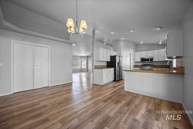 kitchen with open floor plan, appliances with stainless steel finishes, an inviting chandelier, and wood finished floors