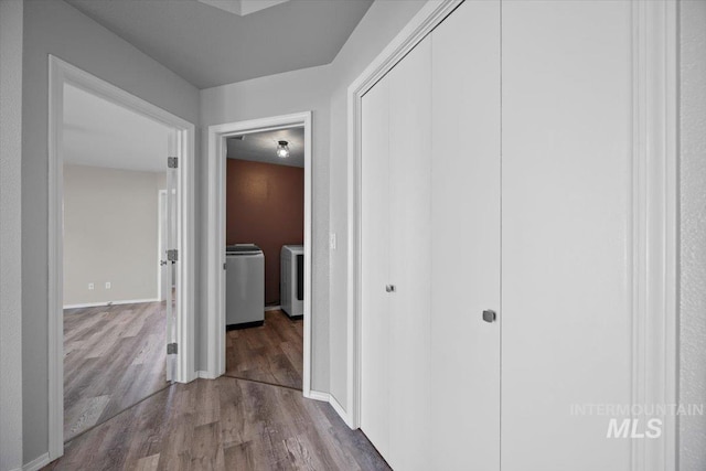 corridor with washer and dryer, baseboards, and wood finished floors