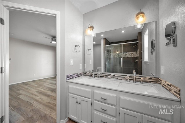 bathroom featuring a sink, ceiling fan, a shower stall, and wood finished floors