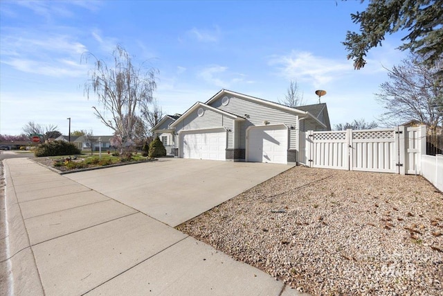 view of property exterior with a garage, driveway, fence, and a gate