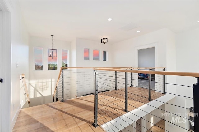 hallway with hardwood / wood-style floors and a chandelier