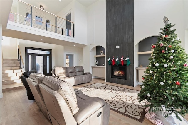 living room featuring a fireplace, a high ceiling, light hardwood / wood-style floors, and built in features