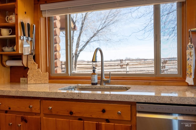 kitchen with a sink, plenty of natural light, stainless steel dishwasher, and brown cabinetry