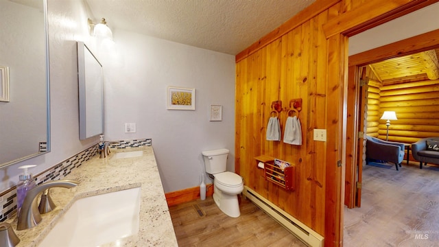 bathroom with a sink, a baseboard radiator, rustic walls, and wood finished floors