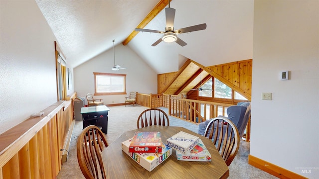 dining space featuring beam ceiling, light colored carpet, high vaulted ceiling, and baseboards