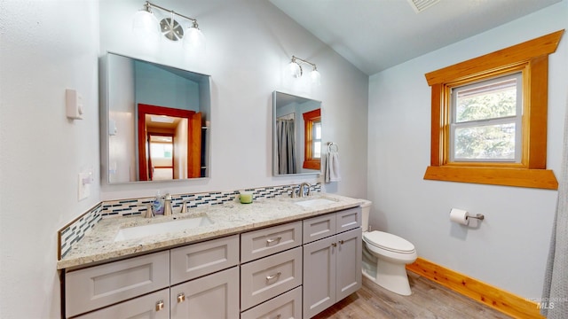 full bath with toilet, wood finished floors, backsplash, and a sink