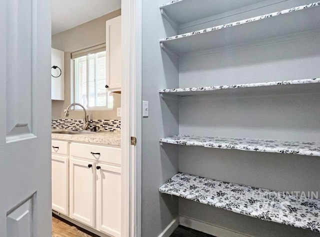 interior space featuring backsplash, wood-type flooring, and vanity with extensive cabinet space