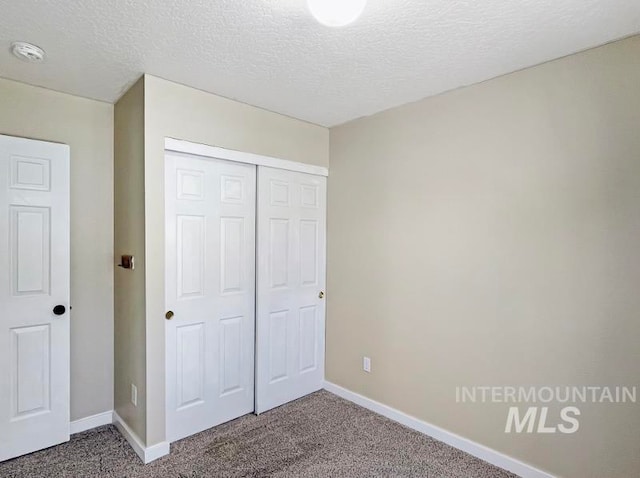 unfurnished bedroom with dark carpet, a closet, and a textured ceiling