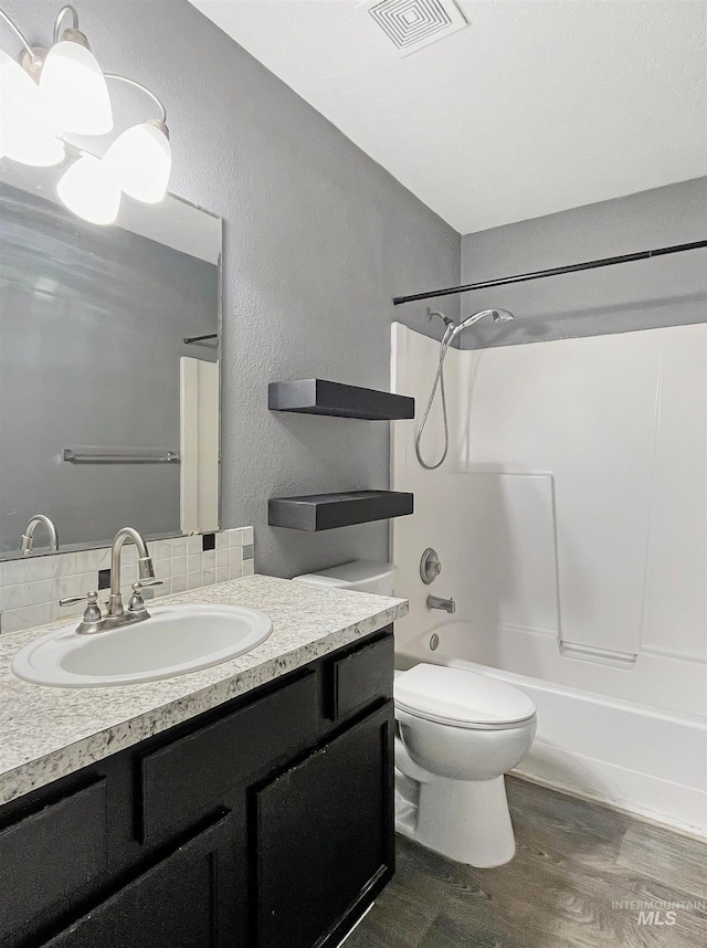 full bathroom featuring hardwood / wood-style floors, tub / shower combination, tasteful backsplash, vanity, and toilet