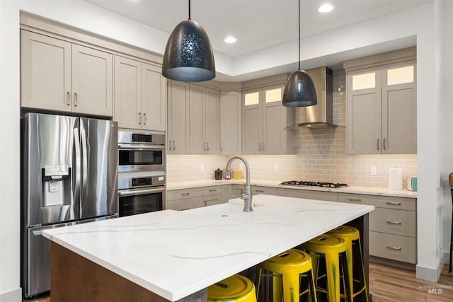 kitchen featuring backsplash, stainless steel appliances, a sink, and wall chimney exhaust hood