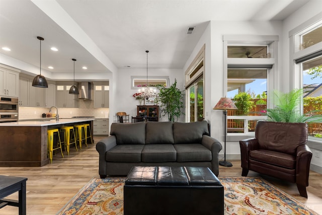 living area featuring recessed lighting, a notable chandelier, light wood-style flooring, and visible vents
