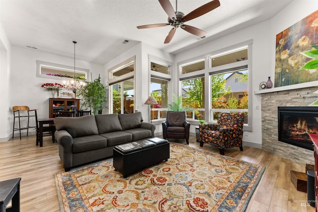 living room featuring visible vents, a fireplace, wood finished floors, baseboards, and ceiling fan with notable chandelier