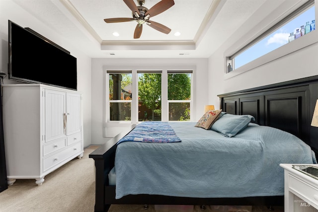 bedroom with light colored carpet, a raised ceiling, ceiling fan, and multiple windows