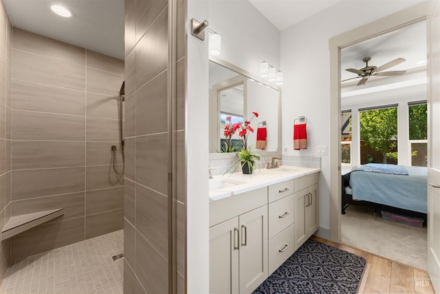 ensuite bathroom with a walk in shower, a ceiling fan, a sink, and wood finished floors