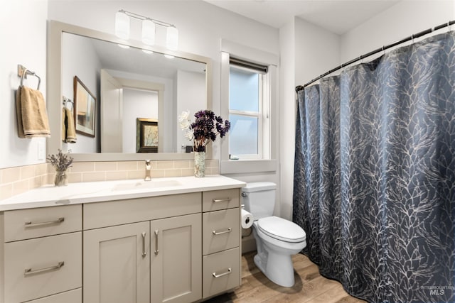 bathroom featuring vanity, decorative backsplash, toilet, and wood finished floors