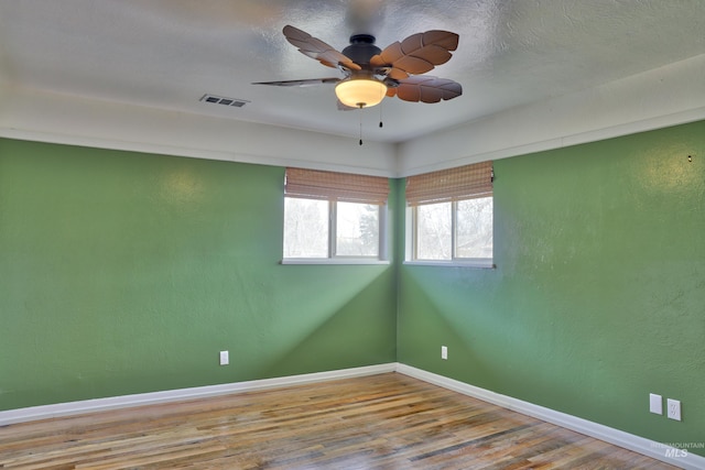 spare room featuring baseboards, visible vents, wood finished floors, and ceiling fan