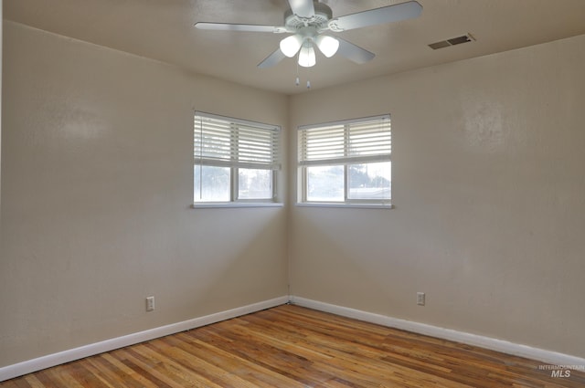 unfurnished room featuring baseboards, visible vents, and wood finished floors