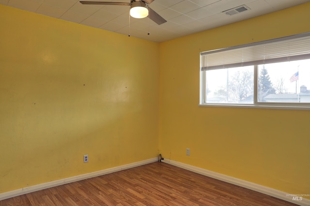 unfurnished room with wood finished floors, ceiling fan, visible vents, and baseboards