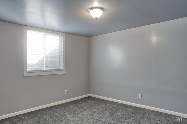 spare room with dark colored carpet and baseboards