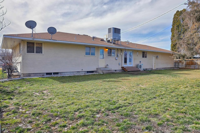 back of house with fence, entry steps, central AC unit, and a yard