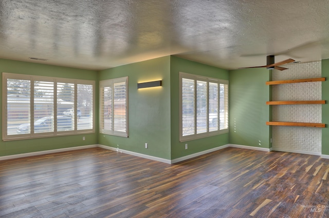 spare room featuring a textured ceiling, wood finished floors, and baseboards