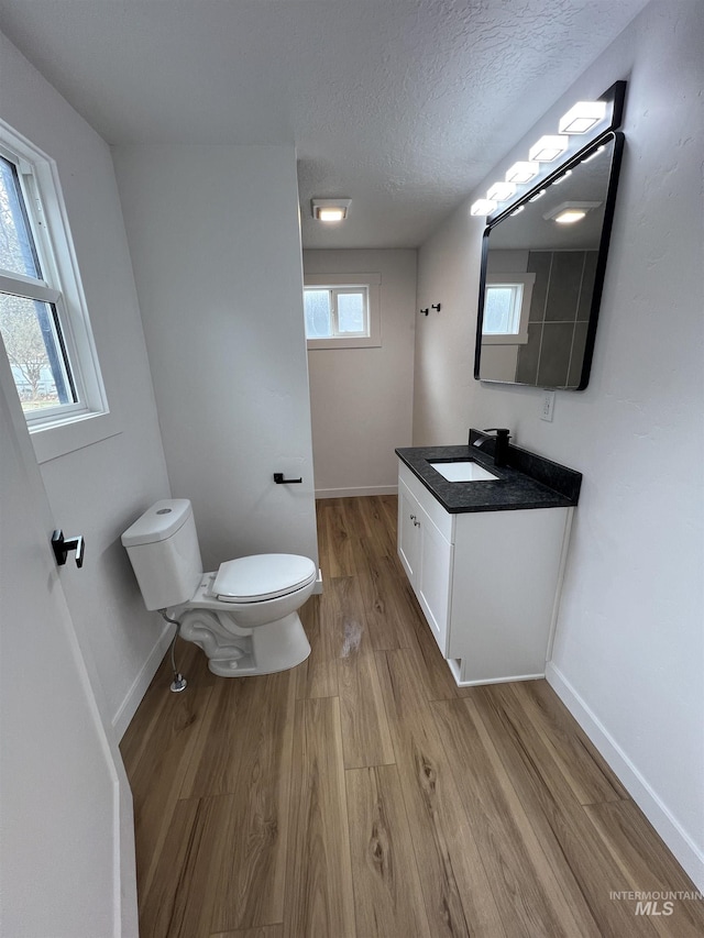 bathroom featuring plenty of natural light, toilet, wood finished floors, and a textured ceiling