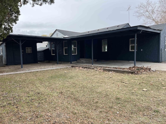 rear view of house featuring a carport, a patio area, and a lawn