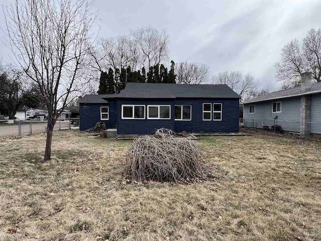 back of property with a lawn and fence