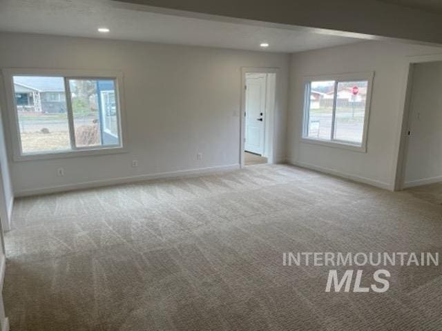 empty room featuring recessed lighting, baseboards, plenty of natural light, and carpet flooring