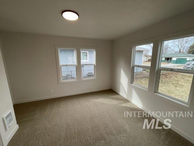 unfurnished room featuring visible vents, light colored carpet, and baseboards